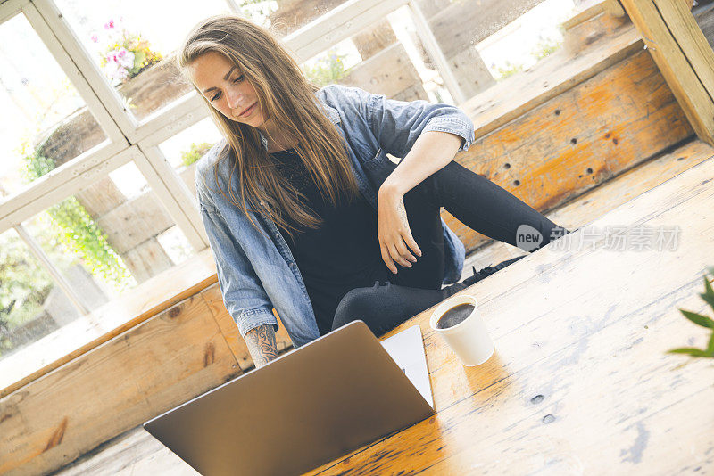 Young female working with laptop on a rustic café